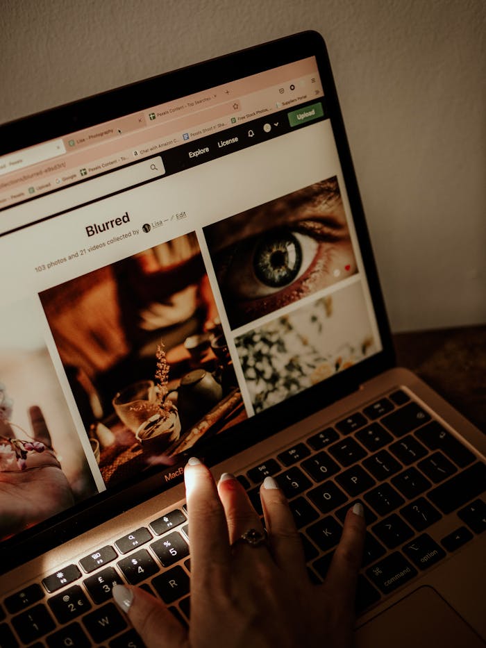 services-01 Hand browsing stock images on laptop with warm sunlight casting shadows indoors.